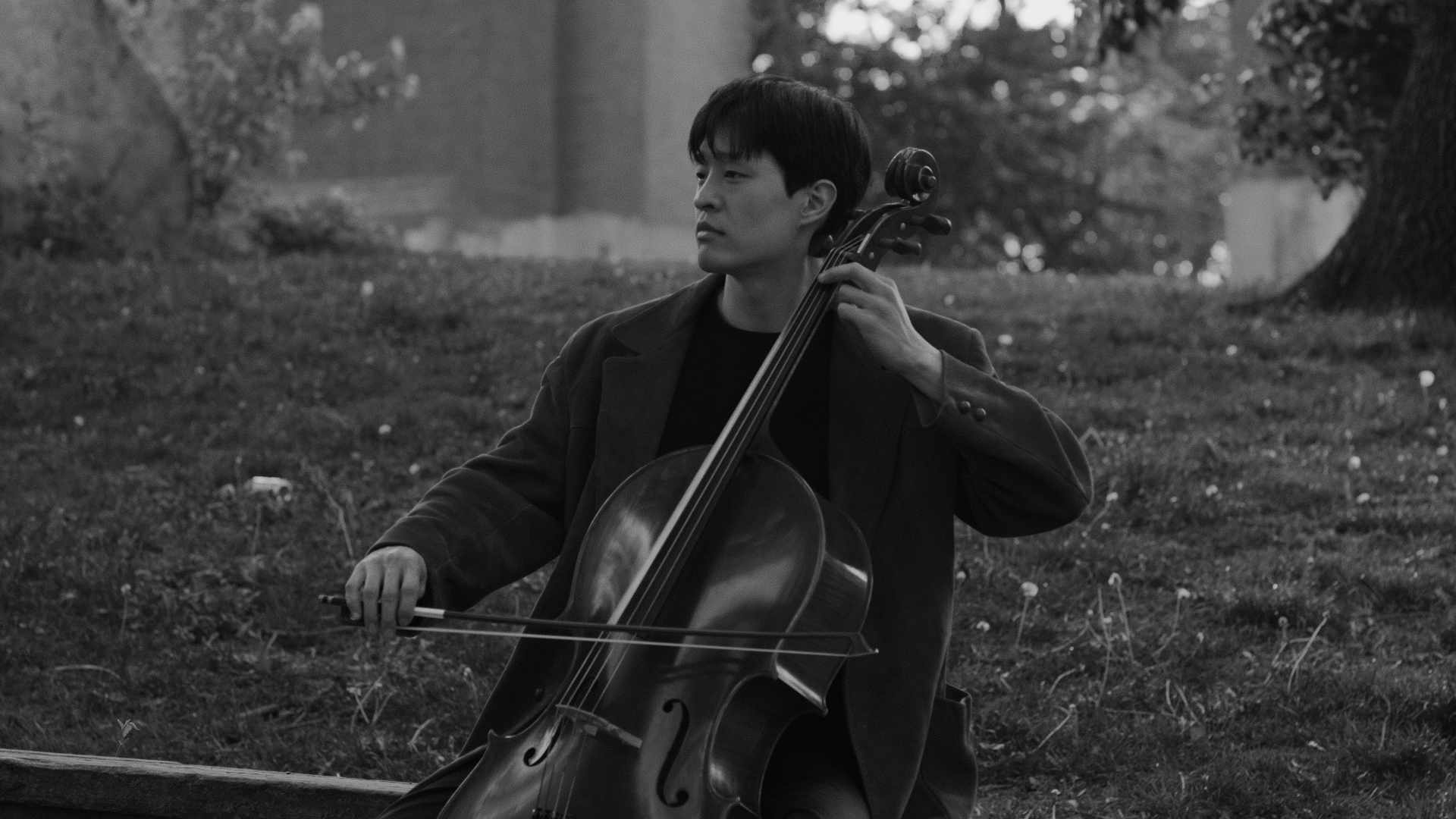 Joseph seated outdoors with his cello